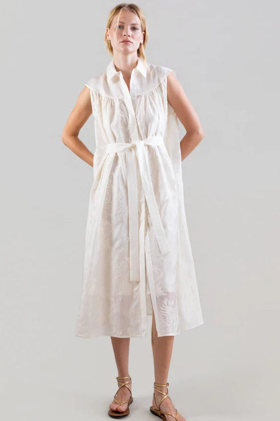 Woman wearing a white sleeveless dress against a plain background