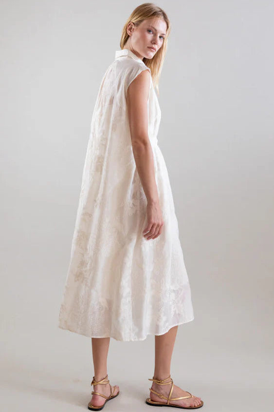 Woman wearing a white dress with a cape on a plain background